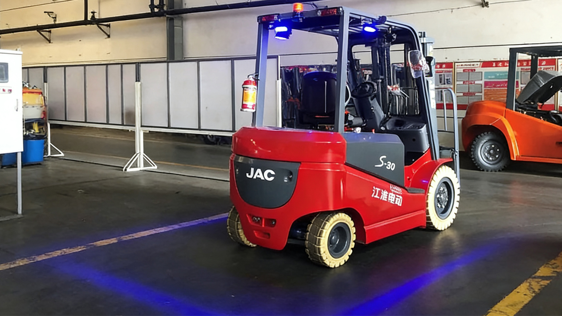 A JAC forklift truck equipped with the JAC TruckSpot reverses out of the hall at dusk.