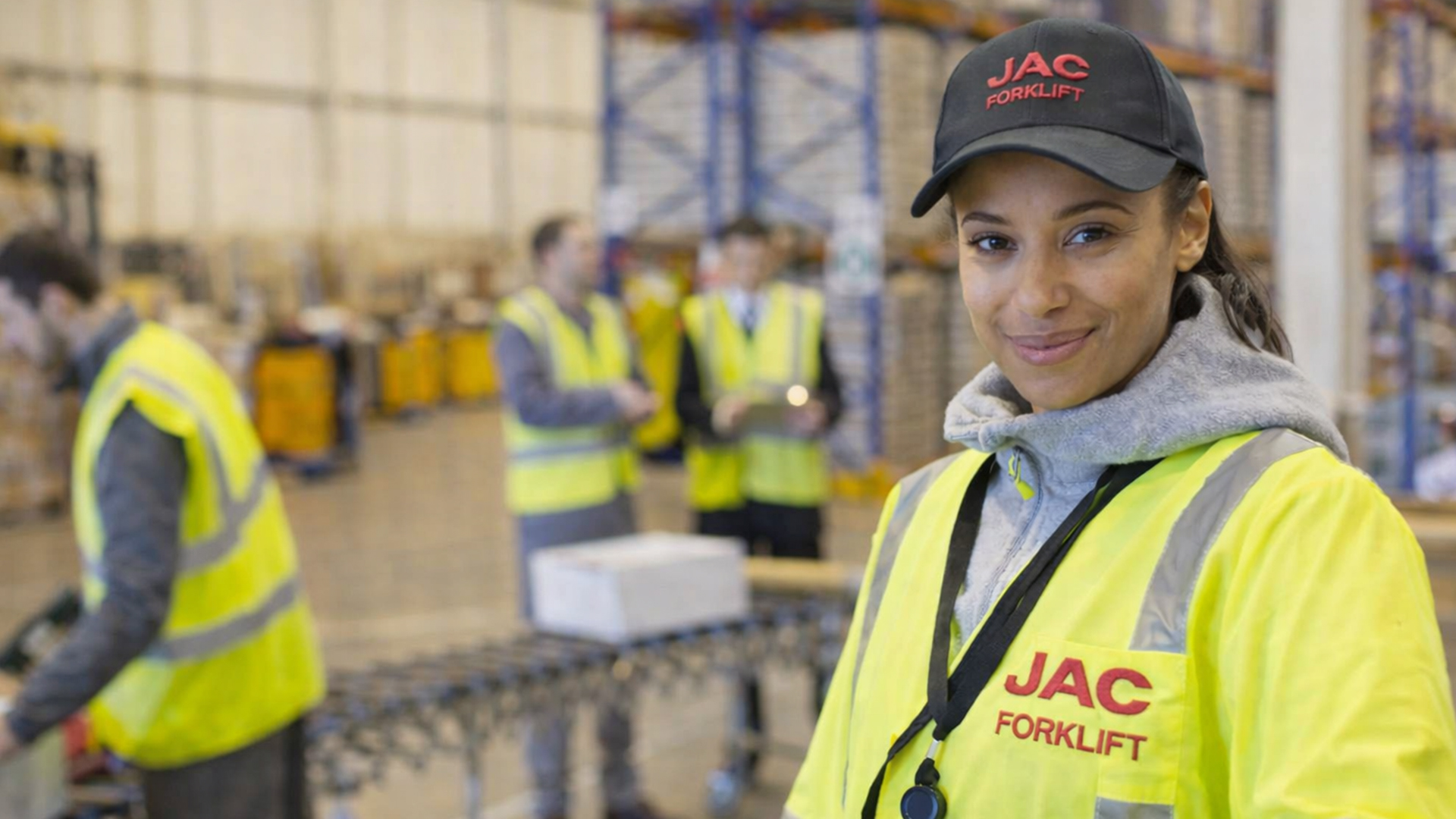 Employee of JAC Forklift sits in a forklift truck and smiles at the camera.